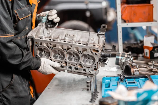 Mecánico de desmontaje del motor, revisión.. Motor en un soporte de reparación con pistón y varilla de conexión de la tecnología automotriz. Interior de un taller de reparación de automóviles . — Foto de Stock