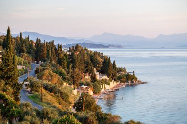 Sahilde yaz gündoğumu, Korfu Adası, Yunanistan. Sahil, adanın başkenti ve Arnavut Dağları manzarası