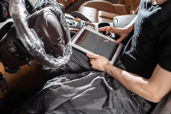 Computer diagnostics of electronic systems of the car. Car mechanic maintains a vehicle with the help of a diagnostic tablet computer. Modern technology in the car repair shop.