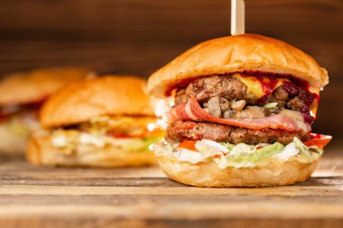 BBQ kömür üzerine pişmiş et ile üç büyük Burger. Ahşap arka planda öğle yemeği. Hızlı gıda ve sağlıksız gıda kavramı