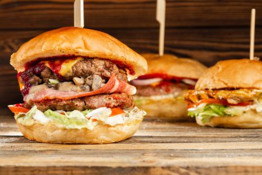 BBQ kömür üzerine pişmiş et ile üç büyük Burger. Ahşap arka planda öğle yemeği. Hızlı gıda ve sağlıksız gıda kavramı