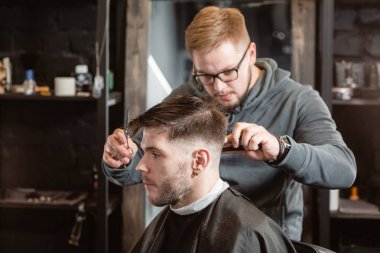 Metal makas ile saç kesimi. Usta saç ve berber erkek sakal keser, Kuaför genç bir adam için saç modeli yapar