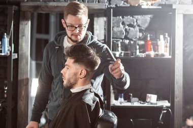 Metal makas ile saç kesimi. Usta saç ve berber erkek sakal keser, Kuaför genç bir adam için saç modeli yapar