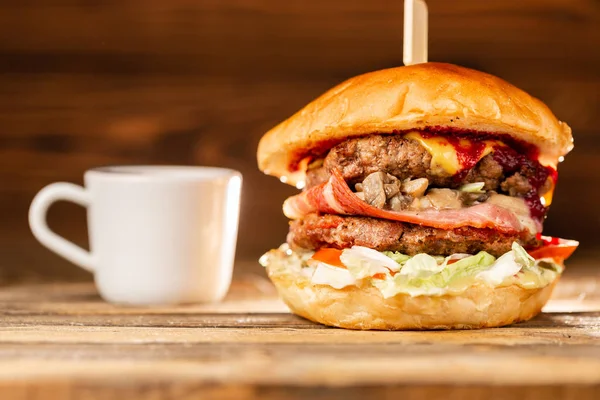 Hamburguesa con carne de res cocida sobre carbón. Almuerzo sobre fondo de madera. El concepto de comida rápida y comida poco saludable — Foto de Stock