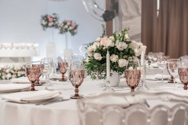 Masanın ortasında çiçek aranjmanı. Düğün yemeği için restoranın iç, misafirler için hazır. Yuvarlak Ziyafet masası servis edilir. Catering konsepti.