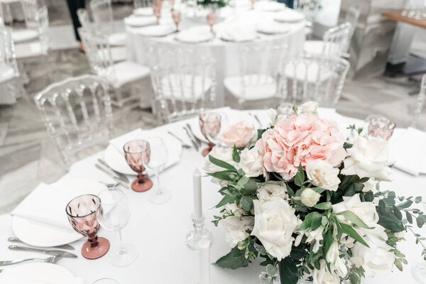 Flower arrangement in the center of the table. Interior of restaurant for wedding dinner, ready for guests. Round Banquet table served. Catering concept.