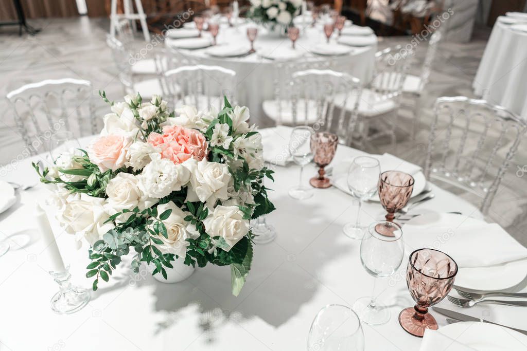 Flower arrangement in the center of the table. Interior of restaurant for wedding dinner, ready for guests. Round Banquet table served. Catering concept.