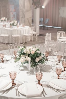 Masanın ortasında çiçek aranjmanı. Düğün yemeği için restoranın iç, misafirler için hazır. Yuvarlak Ziyafet masası servis edilir. Catering konsepti.