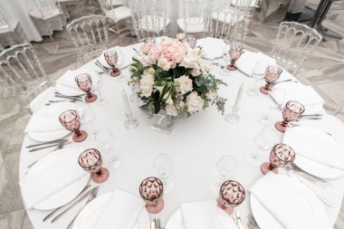 Düğün yemeği için restoranın iç, misafirler için hazır. Yuvarlak Ziyafet masası servis edilir. Çiçek aranjmanı ile dekore edilmiştir. Yemekler, şarap bardakları ve peçeteler. Catering konsepti.