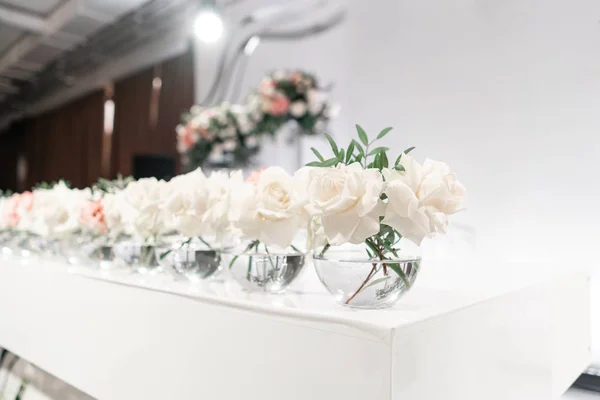 Kleine Blumenarrangements in Kugelglasvasen. den Tisch der Frischvermählten. Innenraum des Restaurants für Hochzeitsessen, bereit für die Gäste. Catering-Konzept. — Stockfoto