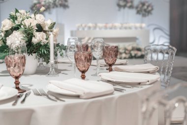 Masanın ortasında çiçek aranjmanı. Düğün yemeği için restoranın iç, misafirler için hazır. Yuvarlak Ziyafet masası servis edilir. Catering konsepti.