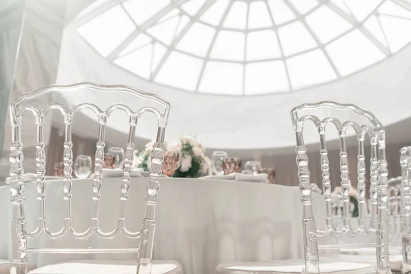 Podává se kulatý stůl. Interiér restaurace k svatební večeři, připraven pro hosty. Zdobené květinovým aranžmá. Nádobí, sklenice na víno a ubrousky. Koncept cateringu. — Stock fotografie