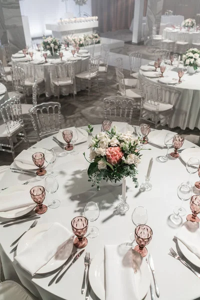 Wine glasses on round Banquet table served. Interior of restaurant for wedding dinner, ready for guests. Decorated with floral arrangement. Dishes, wine glasses and napkins. Catering concept. — 스톡 사진