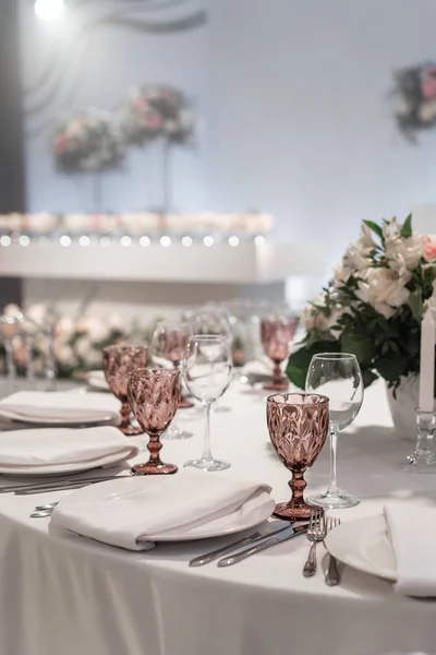 Weingläser auf rundem Banketttisch serviert. Innenraum des Restaurants für Hochzeitsessen, bereit für die Gäste. dekoriert mit Blumenschmuck. Geschirr, Weingläser und Servietten. Catering-Konzept. — Stockfoto