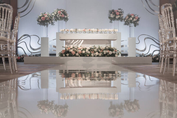 The table of the newlyweds. Small flower arrangements in ball glass vases. Interior of restaurant for wedding dinner, ready for guests. Catering concept.