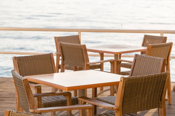 Stoly v kavárně. Letní východ slunce na pobřeží, ostrov Korfu, Řecko. Pláž s lehátky a deštníky s dokonalým výhledem na pevninské řecké hory. — Stock fotografie