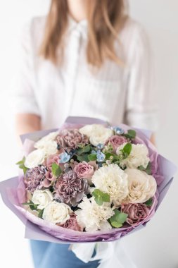 Kadın elinde karışık çiçek güzel buket. bir çiçekçi de çiçekçi çalışmaları. Narin Pastel rengi. Taze kesilmiş çiçek. Beyaz ve leylak rengi