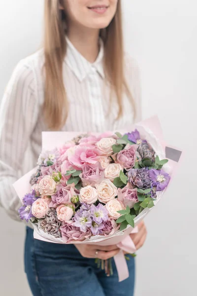 Belo buquê de flores mistas na mão da mulher. o trabalho da florista em uma loja de flores. Cor pastel delicada. Flor fresca cortada. Cor rosa e lilás — Fotografia de Stock