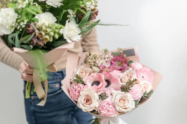 Due bellissimi mazzi di fiori misti nelle mani delle donne. il lavoro del fioraio in un negozio di fiori. Colore pastello delicato. Fiore reciso fresco. Colore verde e rosa — Foto Stock