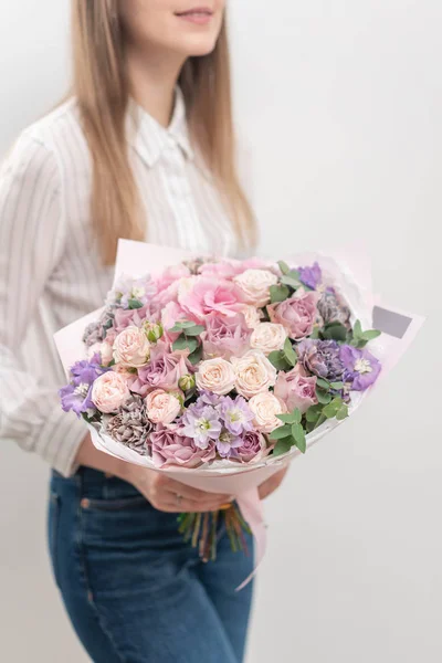 Belo buquê de flores mistas na mão da mulher. o trabalho da florista em uma loja de flores. Cor pastel delicada. Flor fresca cortada. Cor rosa e lilás — Fotografia de Stock