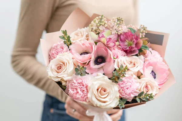 Hermoso ramo de flores mixtas en mano de mujer. el trabajo de la floristería en una florería. Delicado color pastel. Flor recién cortada. Color rosa y blanco — Foto de Stock