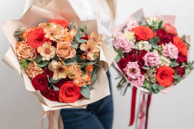 kadın elinde karışık çiçek iki Güzel buketleri. bir çiçekçi de çiçekçi çalışmaları. Narin Pastel rengi. Taze kesilmiş çiçek. Kırmızı ve şeftali rengi