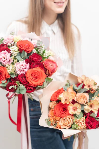 Deux beaux bouquets de fleurs mélangées dans les mains des femmes. le travail du fleuriste dans un magasin de fleurs. Couleur pastel délicate. Fleurs fraîches coupées. Couleur rouge et pêche — Photo