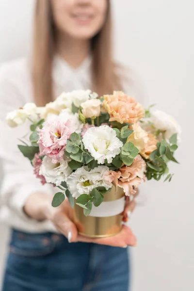 Beautiful floral arrangement of mixed flowers in woman hand. Golden flowerpot. The work of the florist at a flower shop. Delicate Pastel color. Fresh cut flower.