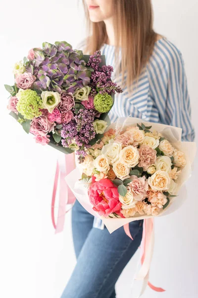 Due bellissimi mazzi di fiori misti nelle mani delle donne. il lavoro del fioraio in un negozio di fiori. Colore pastello delicato. Fiore tagliato fresco . — Foto Stock