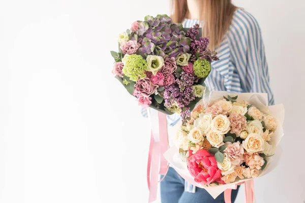 Dos hermosos ramos de flores mixtas en manos de mujeres. el trabajo de la floristería en una florería. Delicado color pastel. Flor fresca cortada . — Foto de Stock