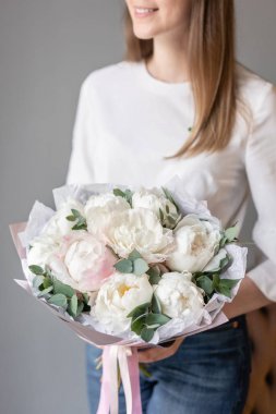 White peonies with eucalyptus in womans hand. Beautiful peony flower for catalog or online store. Beautiful bouquet. Floral shop concept . Fresh cut Flowers delivery