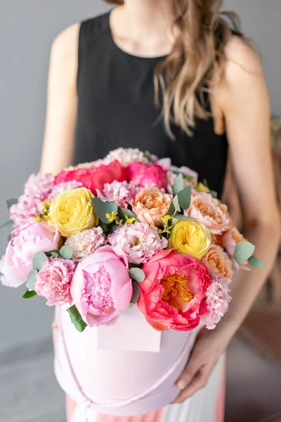 Mercan ve pembe şakayık. Kadın elinde karışık çiçek güzel buketleri. Yuvarlak bir şapka kutusuna paketlenmiş. Çiçek dükkanı konsepti . Taze kesim Çiçekler teslimat — Stok fotoğraf
