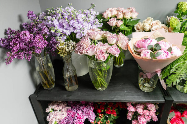 Концепция цветочного магазина. Стеклянные вазы с различными цветами на полках витрин холодильника. Абстрактный цветочный фон. Состав цветов
.