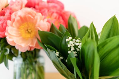 Mercan şakayıkları ve vadinin bahar zambakları ahşap masa üzerinde cam bir vazo ... Katalog veya online mağaza için güzel şakayık çiçek. Çiçek dükkanı konsepti . Güzel taze kesme buketi. Çiçek teslimatı.