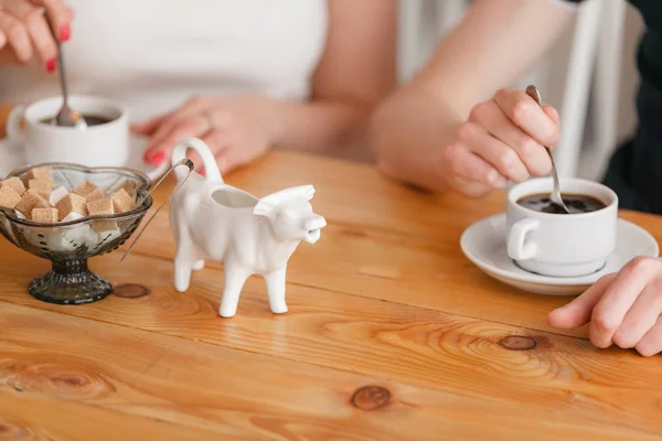 People drink coffee. Coffee cup on wooden table in restaurant. Light morning Breakfast. Gravy boat with milk in the form of cow