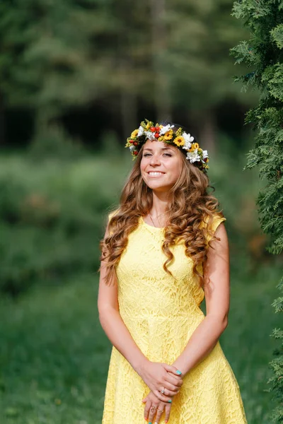 Ritratto giovane ragazza in abito giallo con corona di fiori per la testa. Passeggiate nel parco, Calda giornata estiva . — Foto Stock