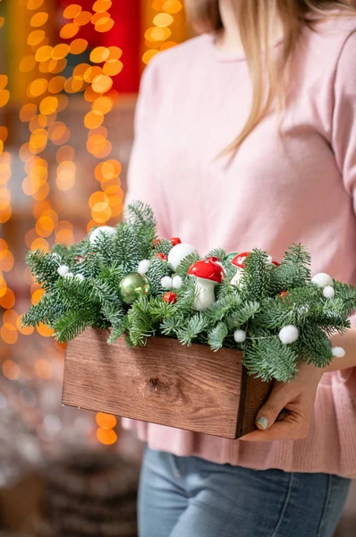 Prachtige feestelijke arrangement van verse sparren met balspeelgoed in een rustieke houten doos. Kerststemming. Bokeh van Garland lichten op de achtergrond. — Stockfoto