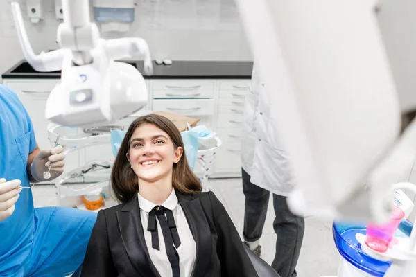 Jovem mulher bonita na cadeira de dentista na clínica odontológica. Medicina, saúde, conceito de estomatologia. dentista a tratar um paciente. Mulher sorrindo — Fotografia de Stock