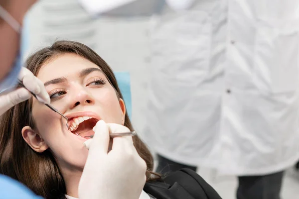 Joven mujer hermosa en la silla del dentista en la clínica dental. Medicina, salud, concepto estomatológico. dentista tratando a un paciente. Mujer sonriendo — Foto de Stock