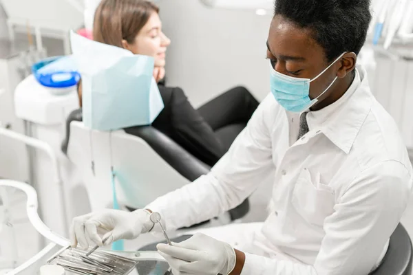 Mladý africký zubař s pacientem. Žena v zubařském křesle na zubařské klinice. Medicína, zdraví, stomatologie. zubař ošetřující pacienta. — Stock fotografie