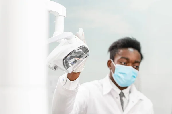 Joven dentista africano en clínica dental. Medicina, salud, concepto estomatológico. dentista tratando a un paciente . — Foto de Stock