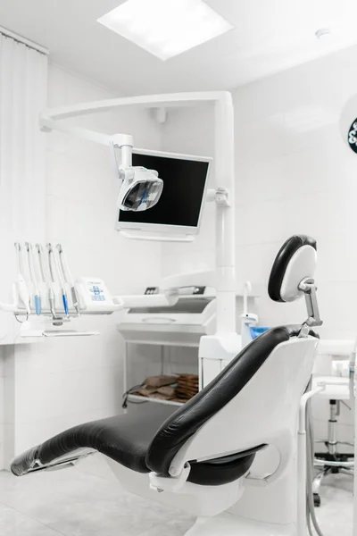 Vertikální pohled zubaře místnosti s černým sedákem. Moderní zubní praxe. Zubařské křeslo a dalšího příslušenství používaného lékaři — Stock fotografie