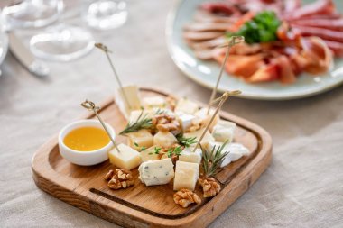 Peynir tabağı. Ceviz ile lezzetli peynir karışımı, ahşap masada bal. Ahşap bir plaka üzerinde yemek tadım. Şarap için yemek. Gala yemeğinde açık büfe.