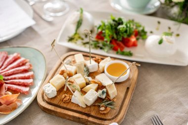 Peynir tabağı. Ceviz ile lezzetli peynir karışımı, ahşap masada bal. Ahşap bir plaka üzerinde yemek tadım. Şarap için yemek. Gala yemeğinde açık büfe.