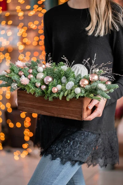 Mooie feestelijke opstelling van verse sparren, roze siervoorwerpen in een rustieke houten doos. Kerststemming. Garland bokeh op de achtergrond. Bokeh van Garland verlichting op de achtergrond. — Stockfoto
