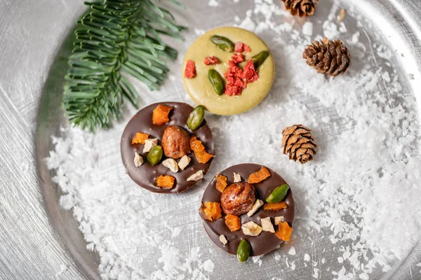 Christmas theme. Handmade chocolates candy. Mini chocolate dessert covered with nuts and dried fruits. Garland lamps bokeh on background. Copy space