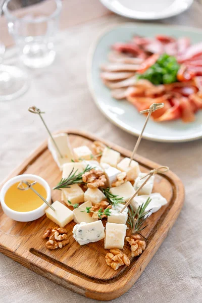 チーズプレートおいしいチーズはクルミ、木製のテーブルの上に蜂蜜と混ぜます。木皿の上で味わう。ワインのための食べ物。ガラディナーでのビュッフェ. — ストック写真