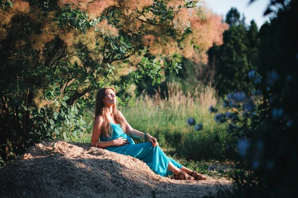 Ung gravid kvinna i parken utomhus. Lugna gravida kvinnan i tredje trimestern. Promenader i den allmänna trädgården. — Stockfoto