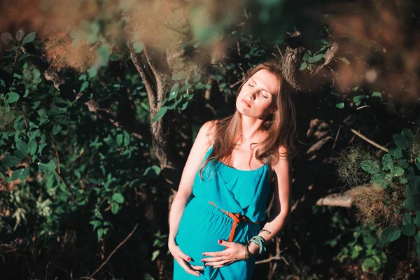 Junge schwangere Frau im Park im Freien. ruhige Schwangere im dritten Trimester. Spaziergang im öffentlichen Garten. — Stockfoto