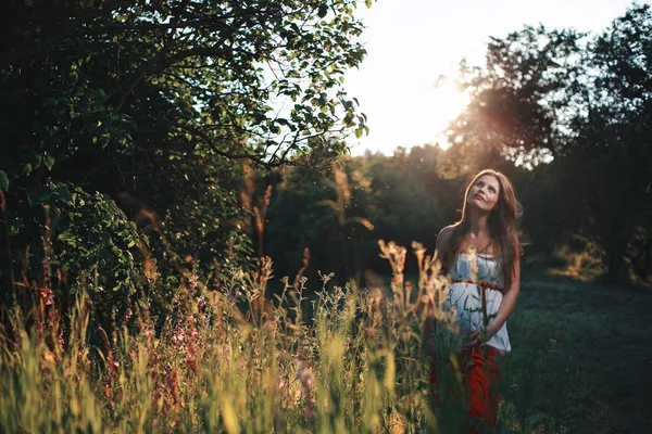 Junge schwangere Frau im Park im Freien. ruhige Schwangere im dritten Trimester. Wandern im öffentlichen Garten. Sonnenuntergang im Wald — Stockfoto